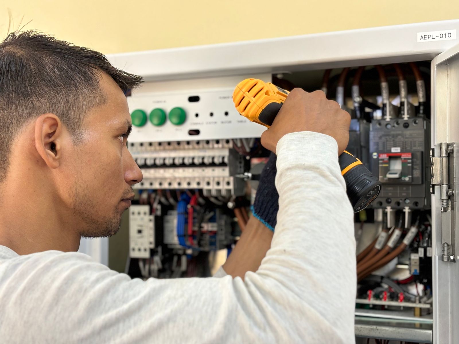 Electrician using a drill on an indoor circuit breaker panel
